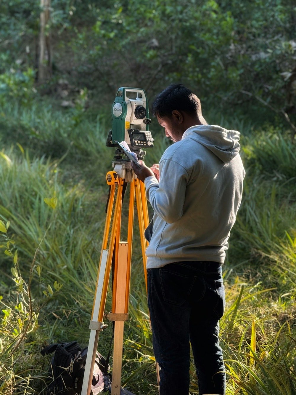 A survey technician taking measurements with a total station during fieldwork